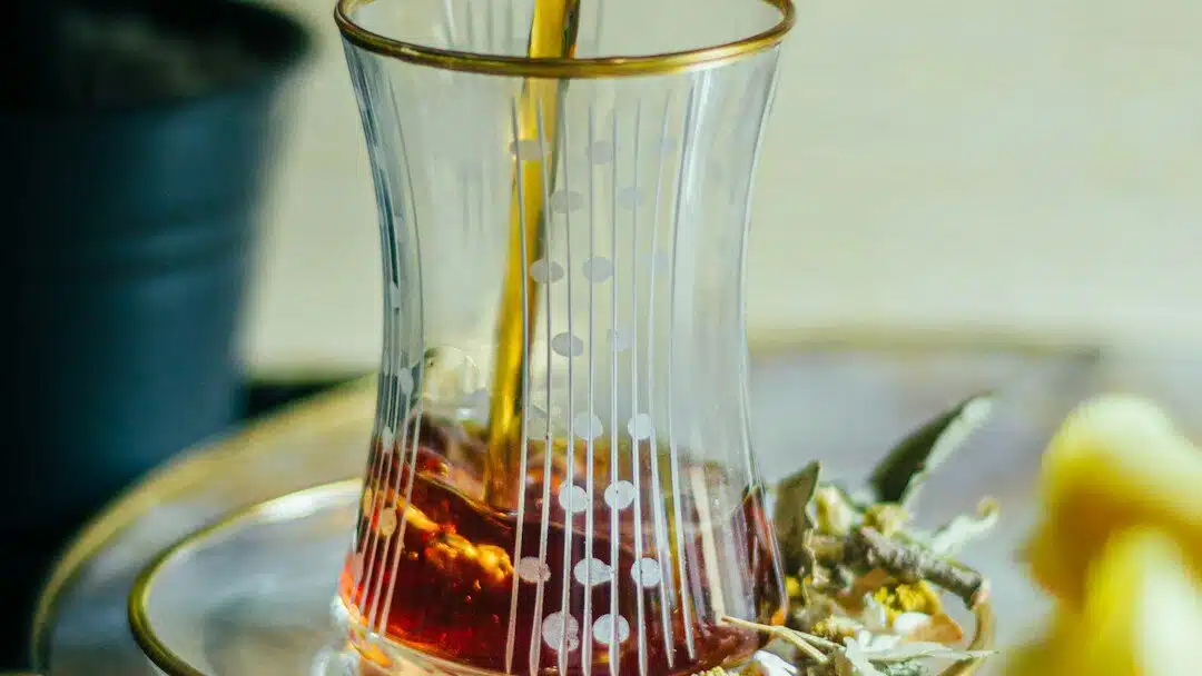 a pitcher pouring tea into a glass cup