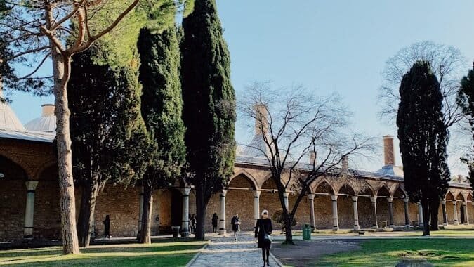 Istanbul's Must-Visit Historical Sites and Museums person walking on sidewalk at Topkapi Palace near trees during daytime