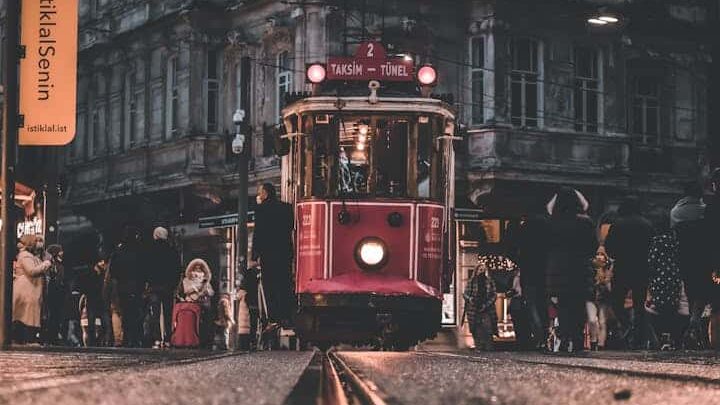 A vintage tram on Istiklal Avenue, Istanbul, captured in a busy night scene with pedestrians.