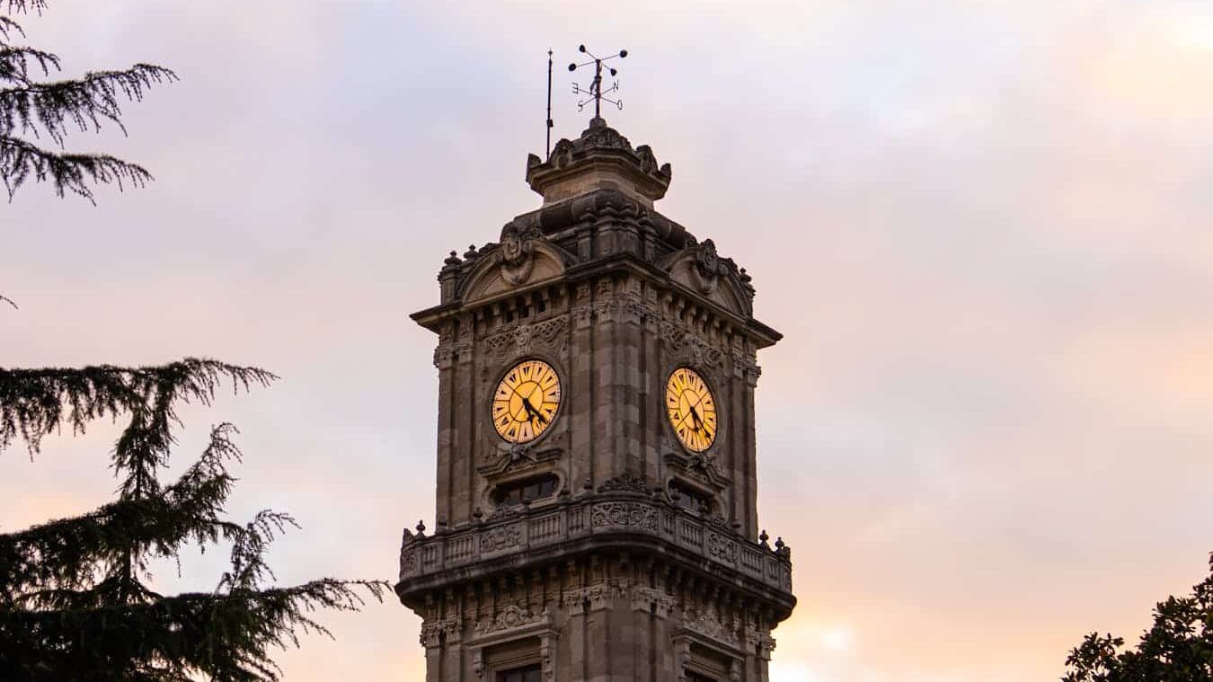 Elegant view of the Dolmabahçe Palace clock tower in Istanbul at sunset.