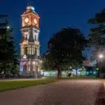 Illuminated Dolmabahçe Clock Tower at night in a tranquil park setting, Istanbul