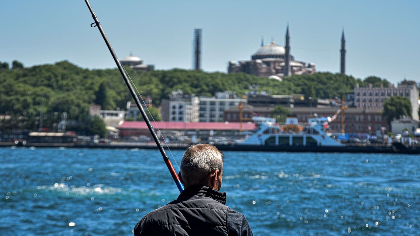 Karaköy - A man fishing on a lake with a city in the background
