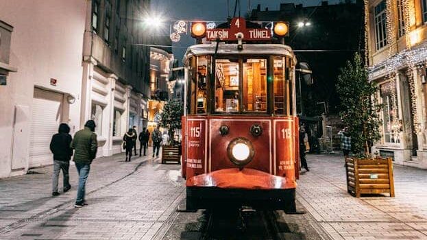 A vintage red tram travels through a lit street in Istanbul at night, capturing urban charm.