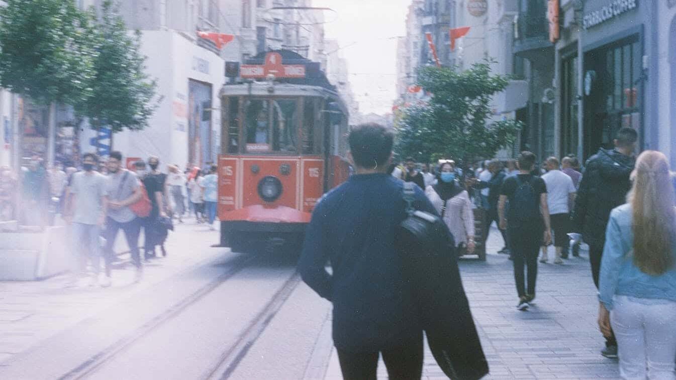 Vibrant city street scene with people and a historic tram, capturing urban life.