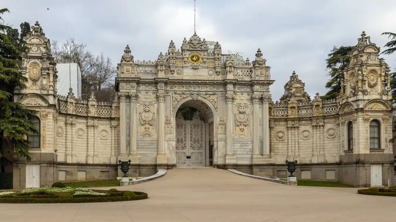 You can enter Dolmabahce Palace with MuseumPass Istanbul. A large stone building with a gate and a clock tower