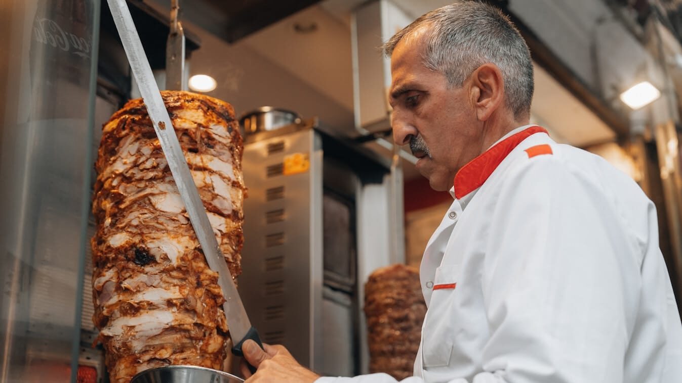 a man cutting a large piece of meat in a kitchen