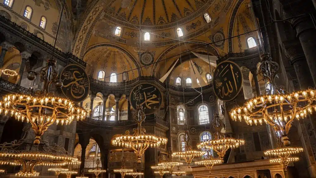 Hagia Sophia Timeline: From Church to Mosque to Museum to Mosque Again a chandelier hangs from the ceiling of a large building