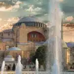 fountain in front of brown concrete building under cloudy sky during daytime