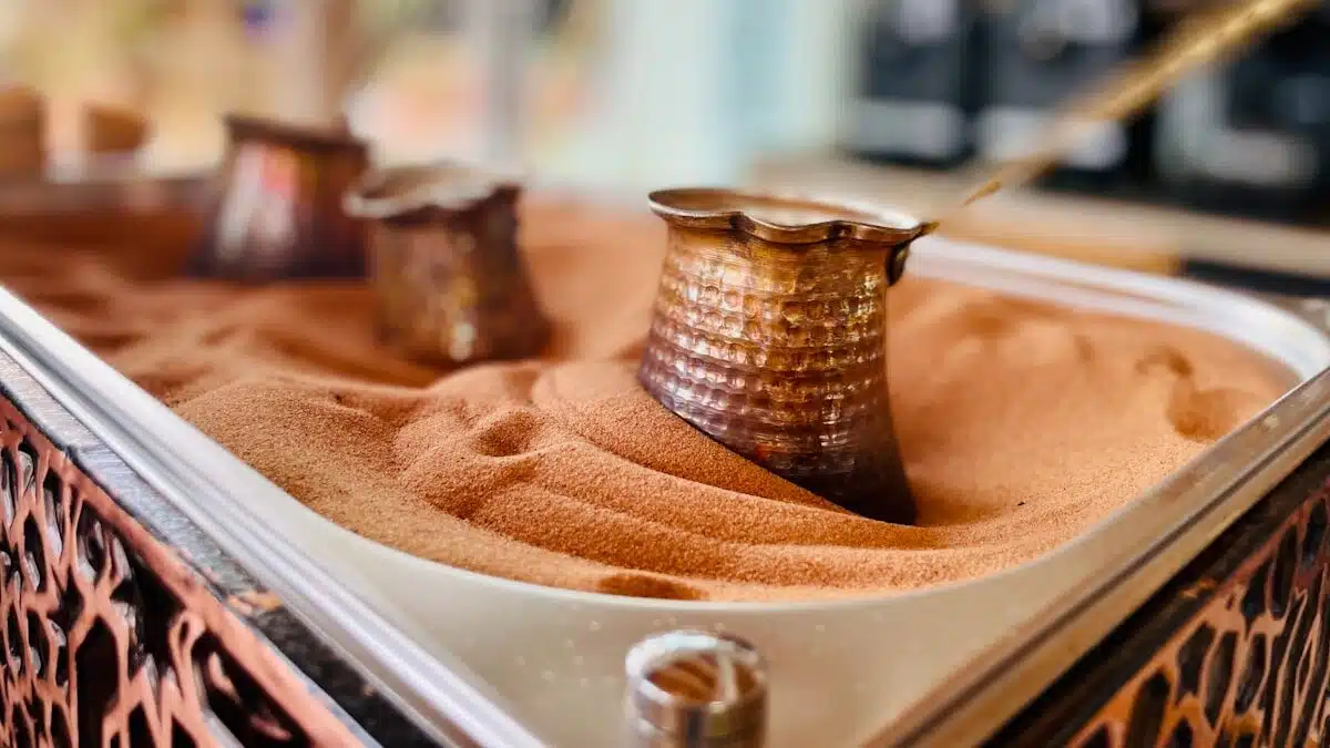a metal container filled with sand and three Turkish coffee pots