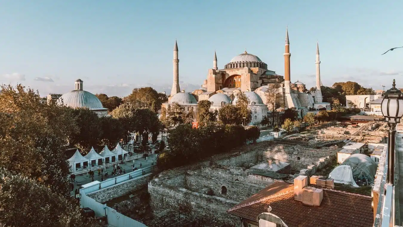 Hagia Sophia Timeline: From Church to Mosque to Museum to Mosque Again a bird flying over a city with a large building