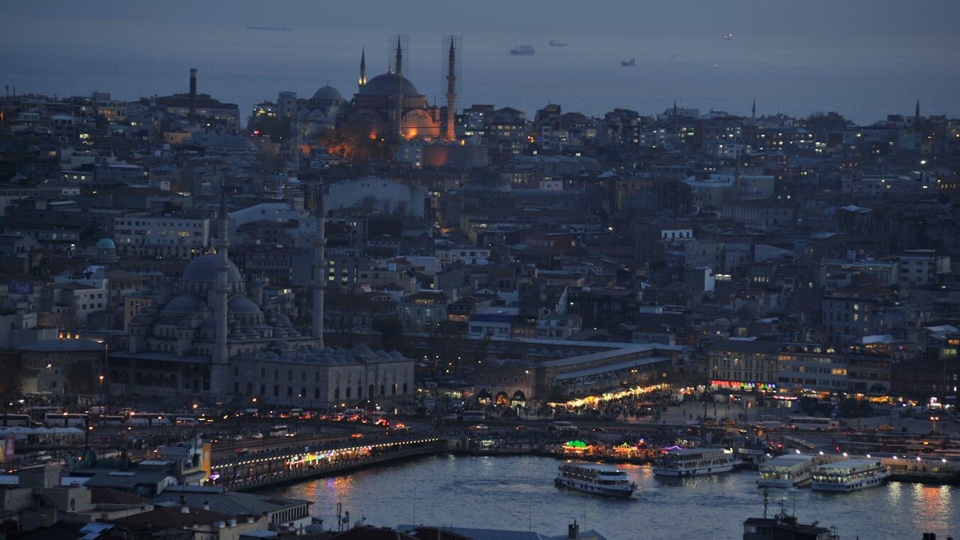 Eminönü - a view of a city at night with boats in the water