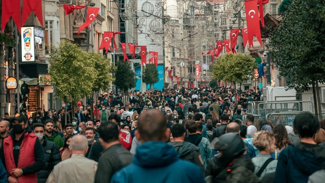 Istiklal Caddesi - a crowd of people walking down a street next to tall buildings