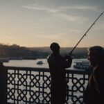 A couple of men standing next to each other on a bridge