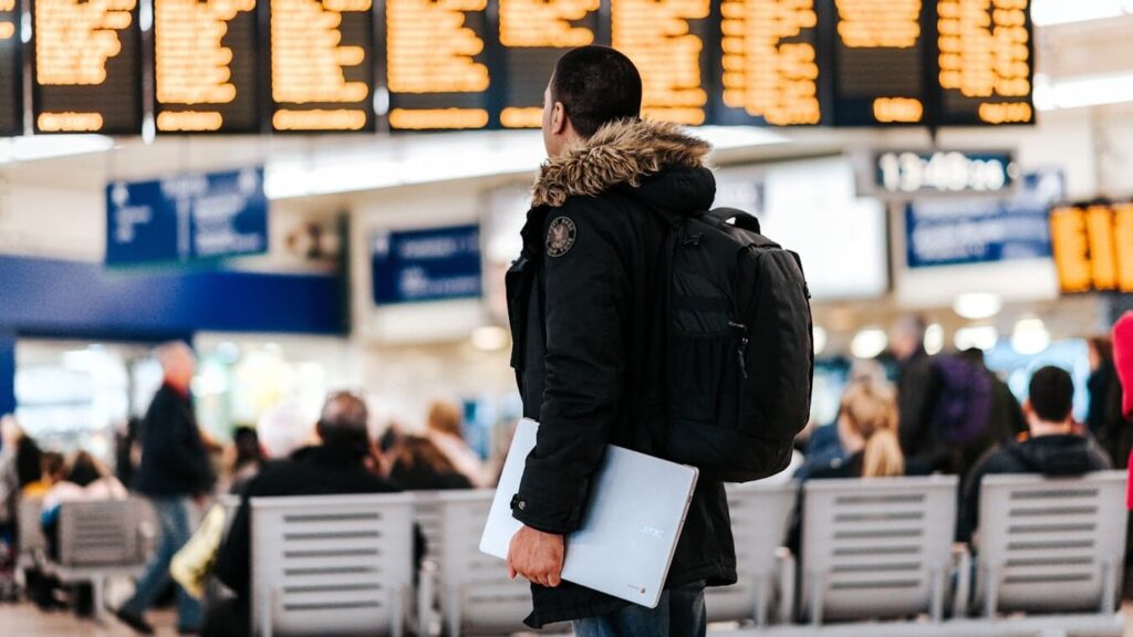Istanbul Visa Guide: Do You Need a Visa for Istanbul? man standing inside airport looking at LED flight schedule bulletin board