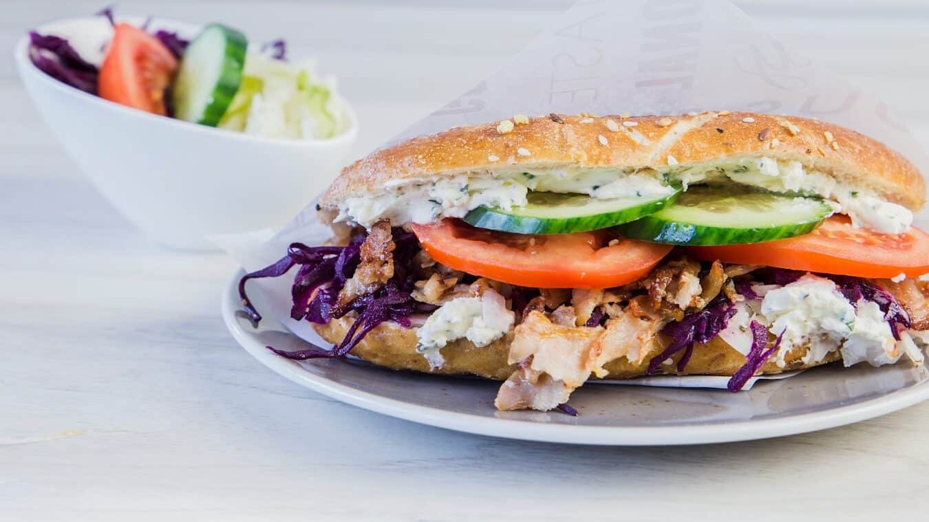 a sdöner kebab andwich on a plate with a side of salad