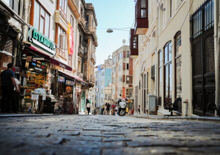 Cobblestone street with shops and people on a sunny day.
